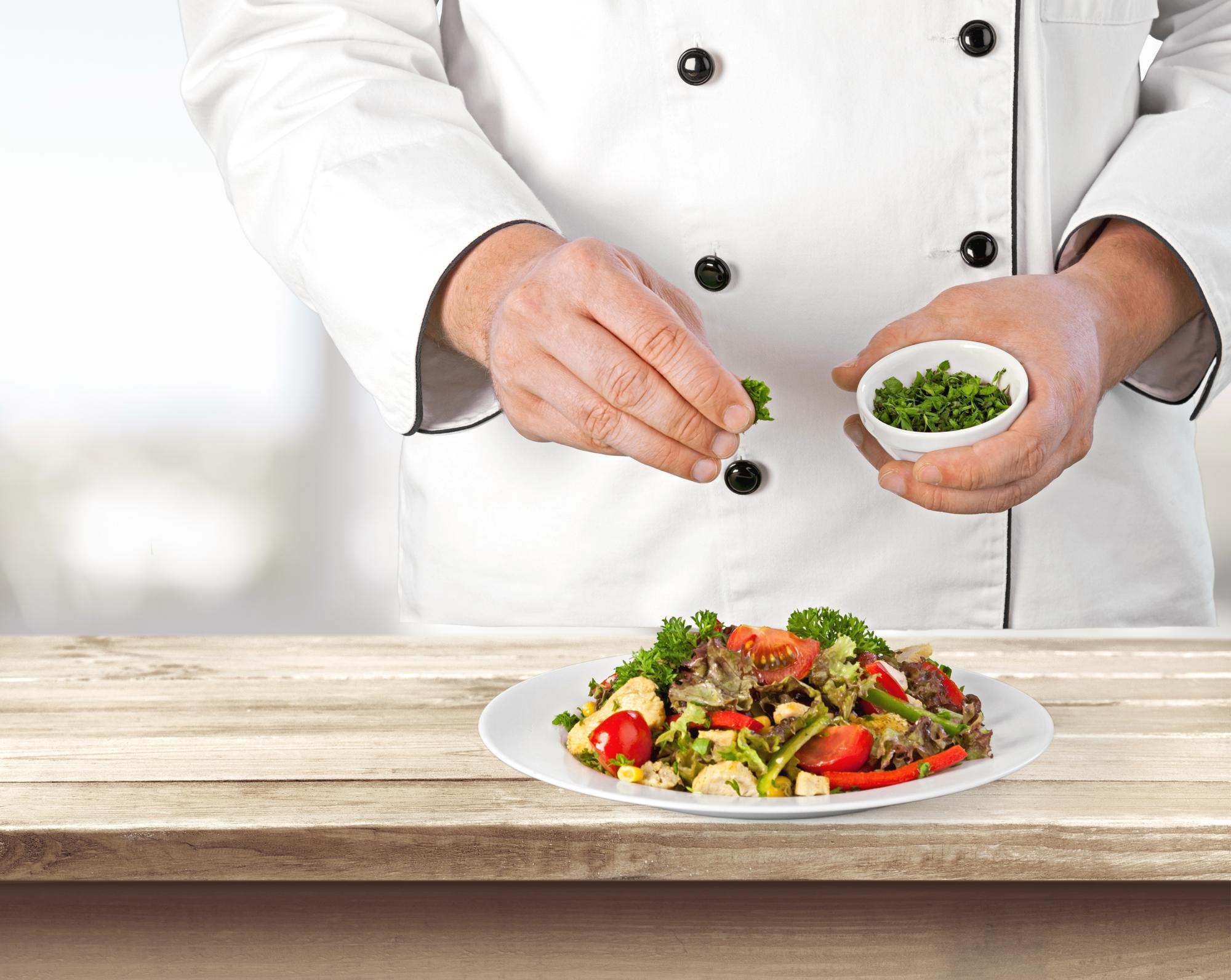 Instructor plating a rustic salad on a wooden table